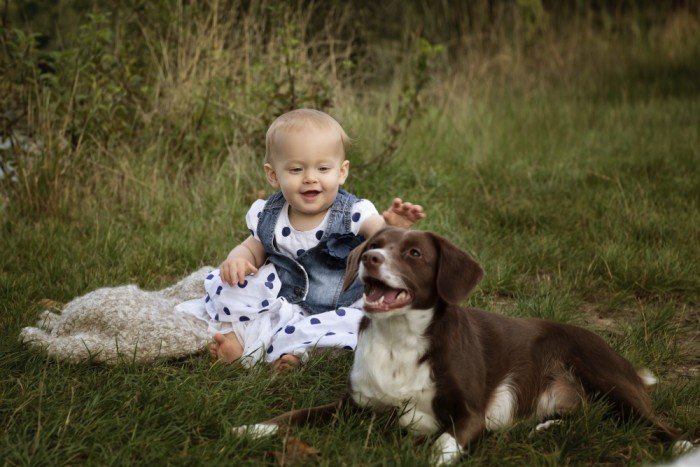 Happy baby reaches for dog