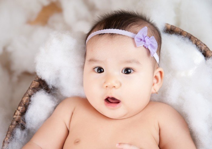 Surprised baby girl with purple bow
