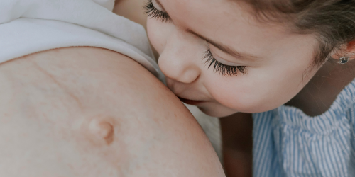 The Complicated Natural Pregnancy child kisses mothers belly